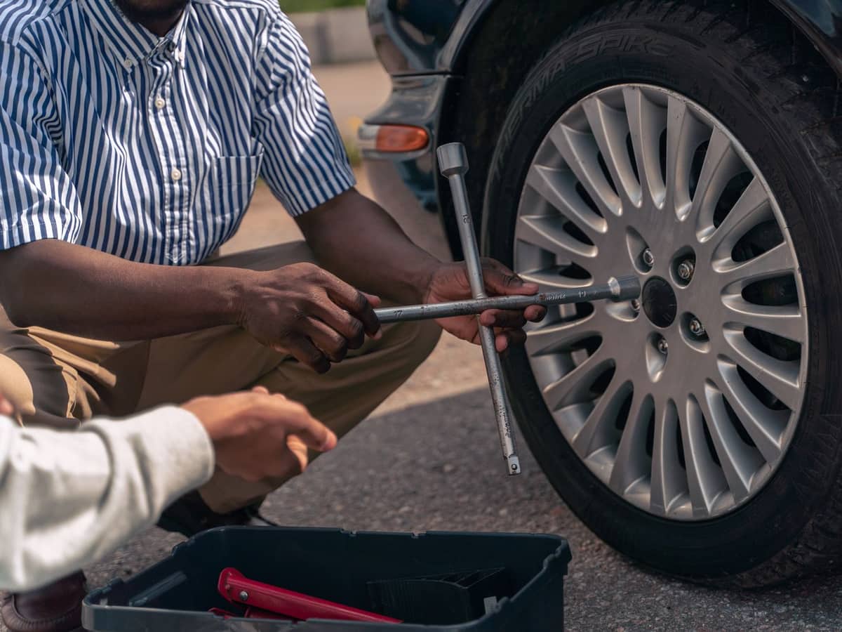 Radwechsel vor Ort: Radschrauben werden am Auto mit dem Kreuzschlüssel gelöst